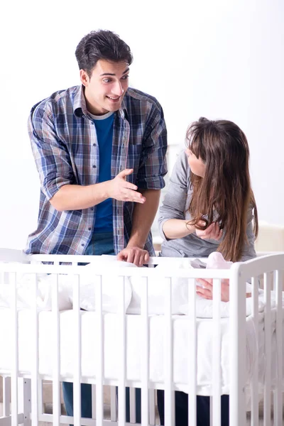 Jonge ouders met hun pasgeboren baby in de buurt van bedje — Stockfoto