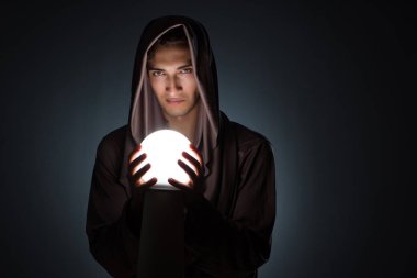 Karanlık odada kristal küreli genç büyücü