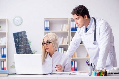 İki doktor teşhis için hastanın röntgen görüntülerini inceliyor.