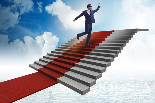 Young businessman climbing stairs and red carpet into sky