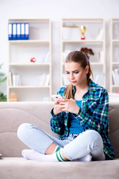 Студентка сидит на диване с мобильным телефоном — стоковое фото