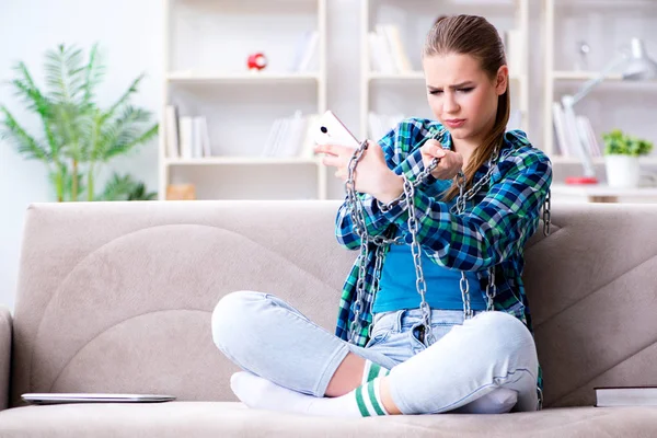 Chained female student with mobile sitting on the sofa — Stock Photo, Image