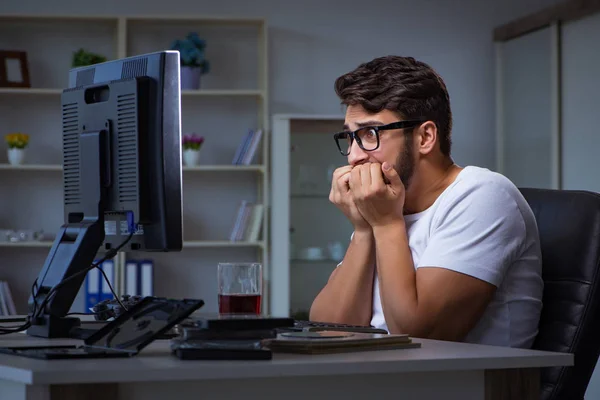 Un tânăr stă târziu la birou pentru a face ore suplimentare — Fotografie, imagine de stoc