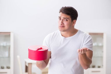 Evde hediye çantası taşıyan genç bir adam karısına sürpriz hazırlıyor.