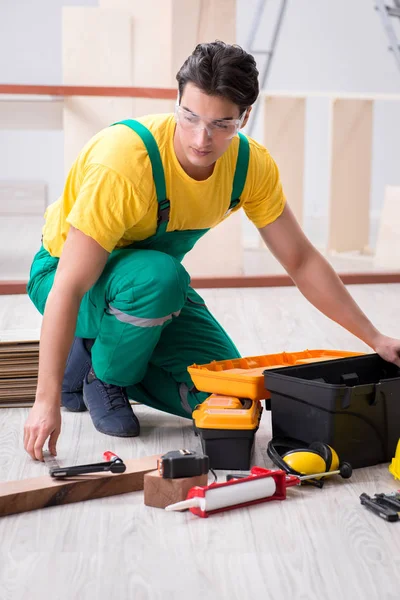 Empreiteiro que trabalha no piso de madeira laminado — Fotografia de Stock