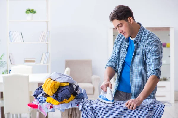 Joven marido haciendo planchado de ropa en casa —  Fotos de Stock