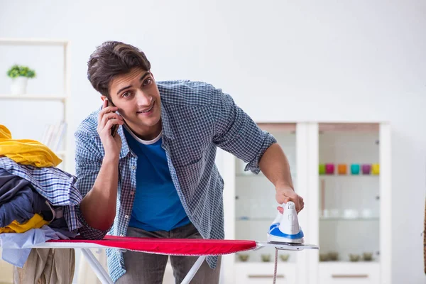 Joven marido haciendo planchado de ropa en casa — Foto de Stock