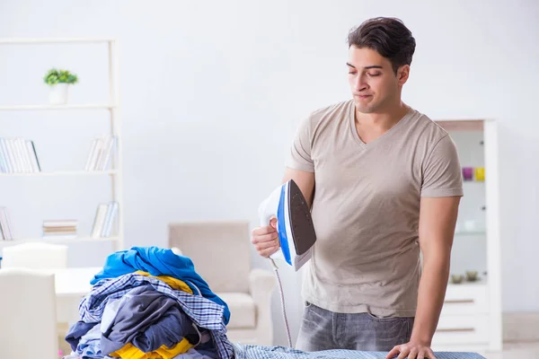 Joven marido haciendo planchado de ropa en casa — Foto de Stock