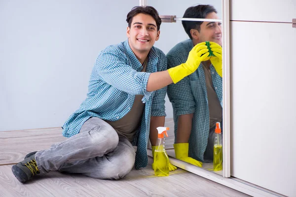 Young man cleaning mirror at home hotel — Stock Photo, Image