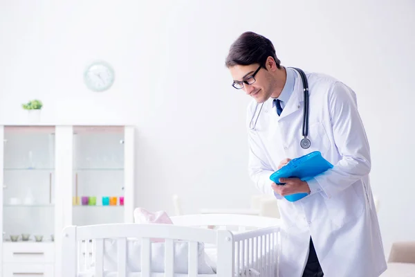 아기 침대 근처에 있는 남자 소아과 의사가 검사를 준비하고 있다 — 스톡 사진