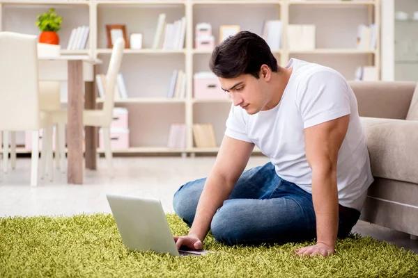Hombre trabajando en el ordenador portátil en casa en el suelo de la alfombra — Foto de Stock