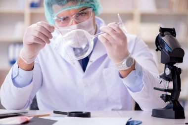 Adli tıp dedektifi suç delilleri üzerinde çalışıyor.