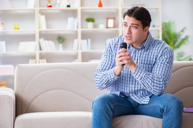 Evde karaoke yapan komik adam.