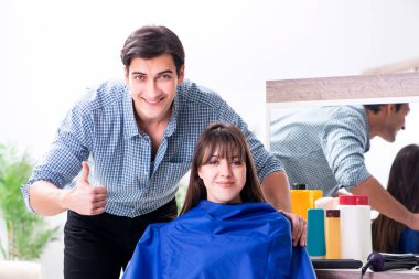 Erkek kuaför kadın için saç kesimi yapıyor.