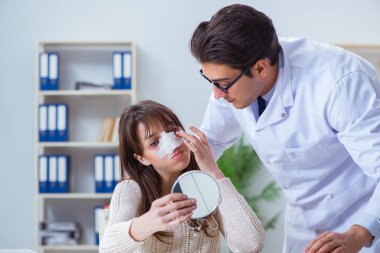 Erkek doktor burun ameliyatı geçirmiş bir hastayla konuşuyor.