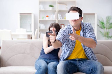 Genç bir aile sanal gerçeklik gözlükleriyle oyun oynuyor.