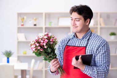 Çiçekçi asistanı bir demet çiçek veriyor.