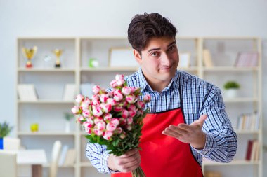 Çiçekçi asistanı bir demet çiçek veriyor.