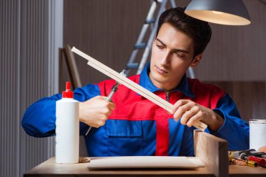 Genç adam ahşap parçaları DIY konseptinde yapıştırıyor.