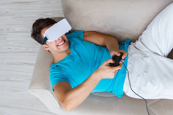 Jovem vestindo óculos VR relaxando no sofá sofá — Fotografia de Stock