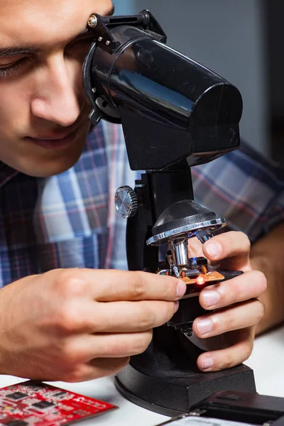 Reparatör försöker reparera bärbar dator med miscroscope — Stockfoto