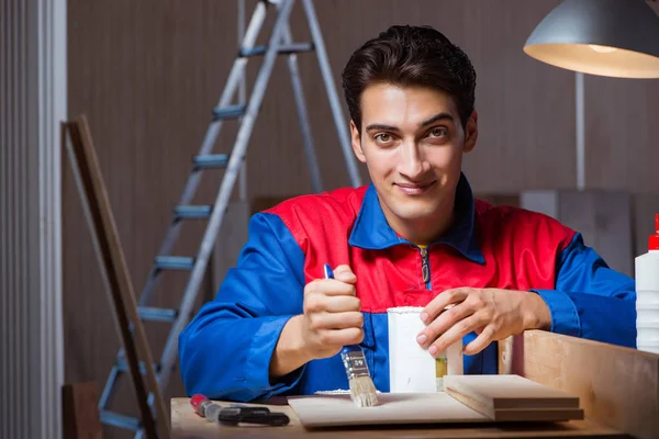 Молодий чоловік склеює шматочки деревини разом у концепції DIY — стокове фото