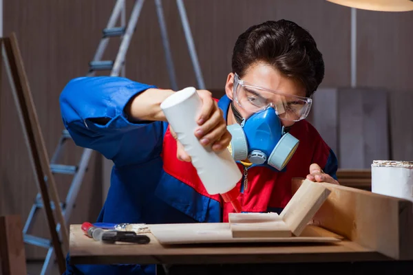 Jovem colando pedaços de madeira juntos no conceito DIY — Fotografia de Stock