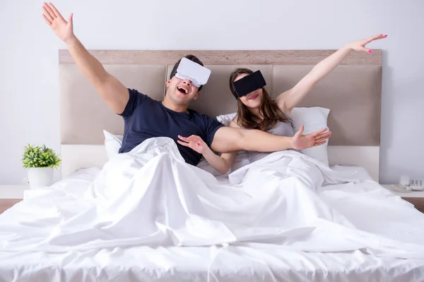 Wife and husband with virtual reality goggles in the bed — Stock Photo, Image