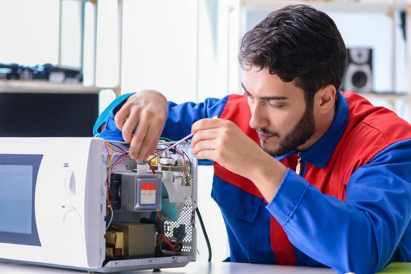 Jeune réparateur fixant et réparant four à micro-ondes — Photo