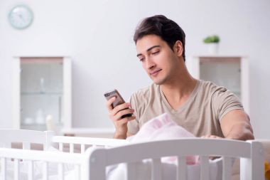 Genç baba evde yeni doğmuş bebekle eğleniyor.