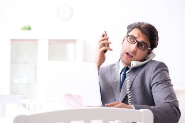 Genç işadamı yeni doğduktan sonra evde çalışmaya çalışıyor. 