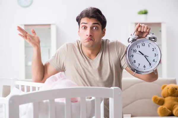 Jonge vader met klok in de buurt van pasgeboren babybedje — Stockfoto