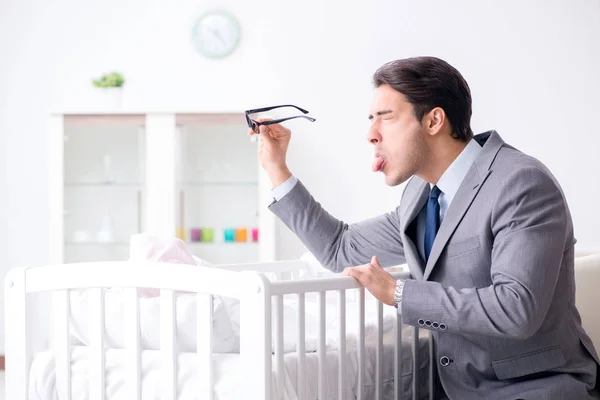 Jovem empresário tentando trabalhar em casa cuidando após o recém-nascido — Fotografia de Stock