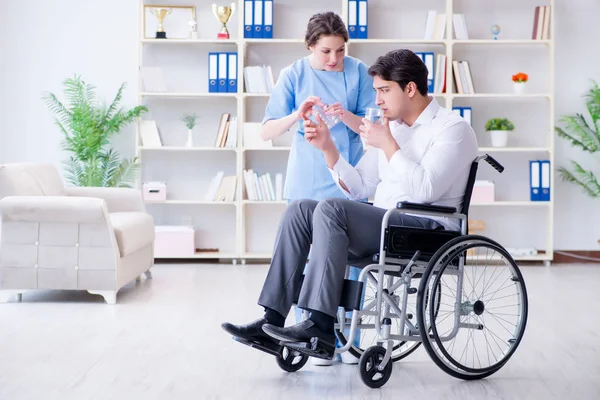 Пациент с ограниченными возможностями на инвалидной коляске посещает врача для регулярной проверки — стоковое фото
