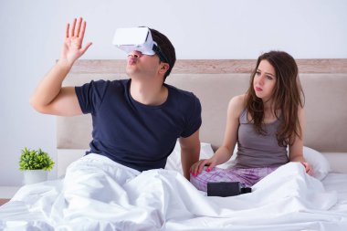 Yatakta sanal gerçeklik gözlüklü eş ve koca.