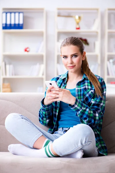 Estudante feminina sentada no sofá com celular — Fotografia de Stock