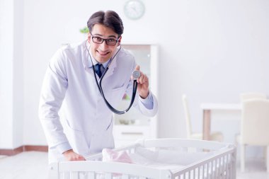 Erkek çocuk doktoru bebek yatağının yanında muayene etmeye hazırlanıyor.