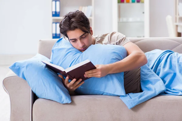 Jovem estudante se preparando para exames universitários na cama com livro — Fotografia de Stock