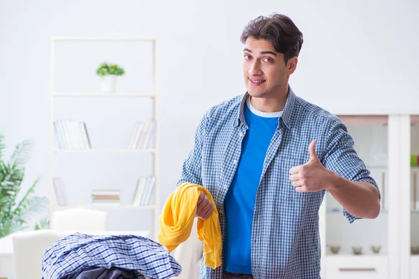 Jovem marido fazendo roupas de engomar em casa — Fotografia de Stock