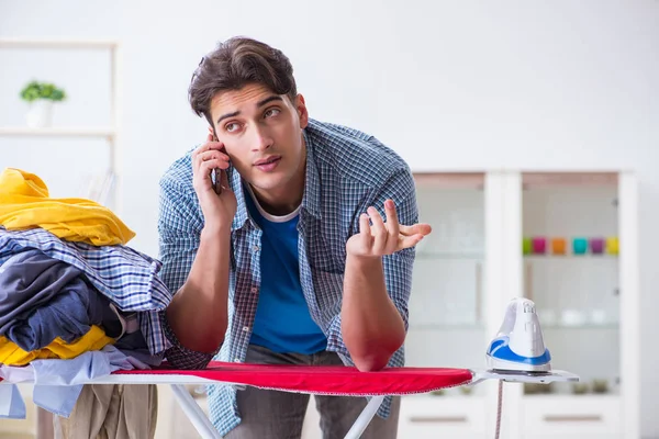 Joven marido haciendo planchado de ropa en casa — Foto de Stock