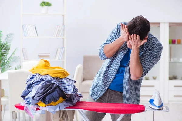 Joven marido haciendo planchado de ropa en casa — Foto de Stock