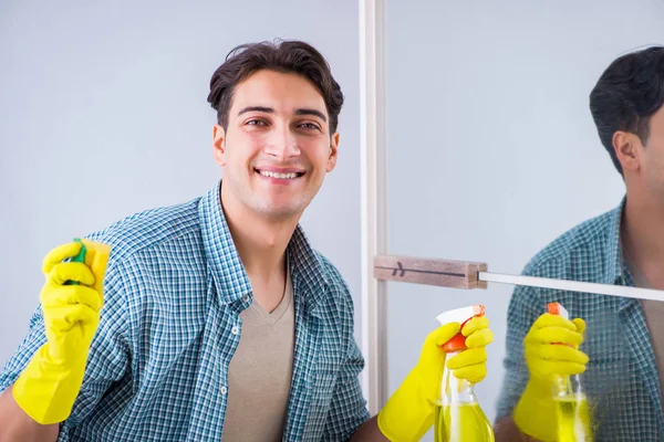 Młody mężczyzna sprzątanie lustro w domu hotel — Zdjęcie stockowe