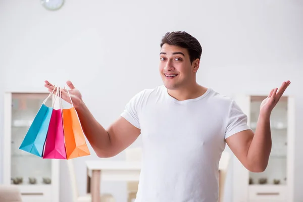 Young man with gift bag at home preparing suprise for wife — Stock Photo, Image