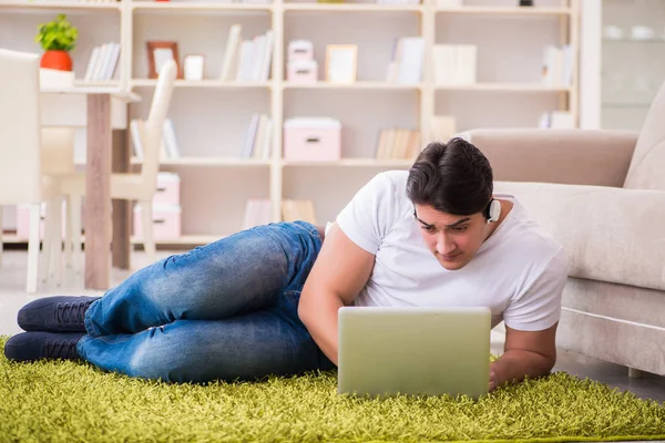 Homem trabalhando no laptop em casa no chão do tapete — Fotografia de Stock