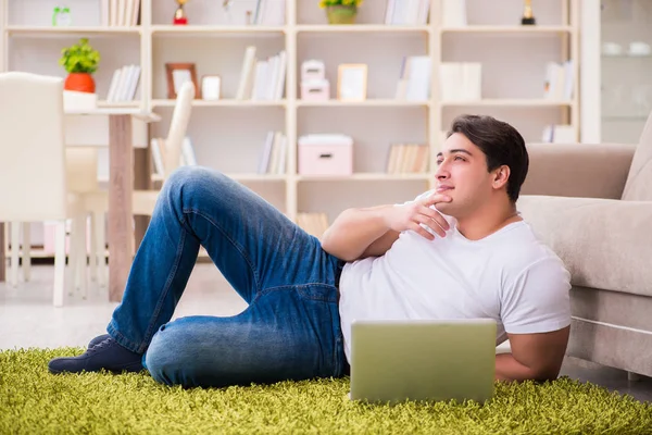 Homem trabalhando no laptop em casa no chão do tapete — Fotografia de Stock