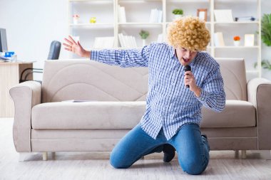 Evde karaoke yapan komik adam.