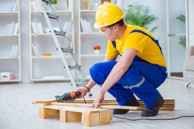 Ahşap palet montajı yapan genç adam.