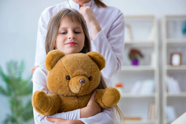 Donna medico femminile esaminando piccola ragazza carina con orso giocattolo — Foto Stock