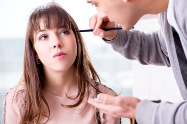 Güzellik salonunda güzel bir kadın için makyaj yapan adam.