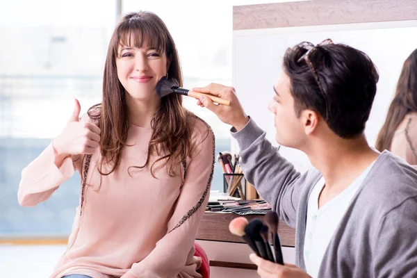 Мужчина делает макияж для симпатичной женщины в салоне красоты — стоковое фото